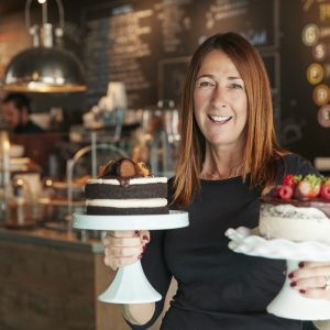 portrait-of-female-owner-with-cakes-on-stands-in-coffee-shop.jpg