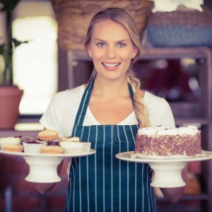 waitress-holding-a-chocolate-cake-and-cupcakes-at-the-coffee-shop.jpg